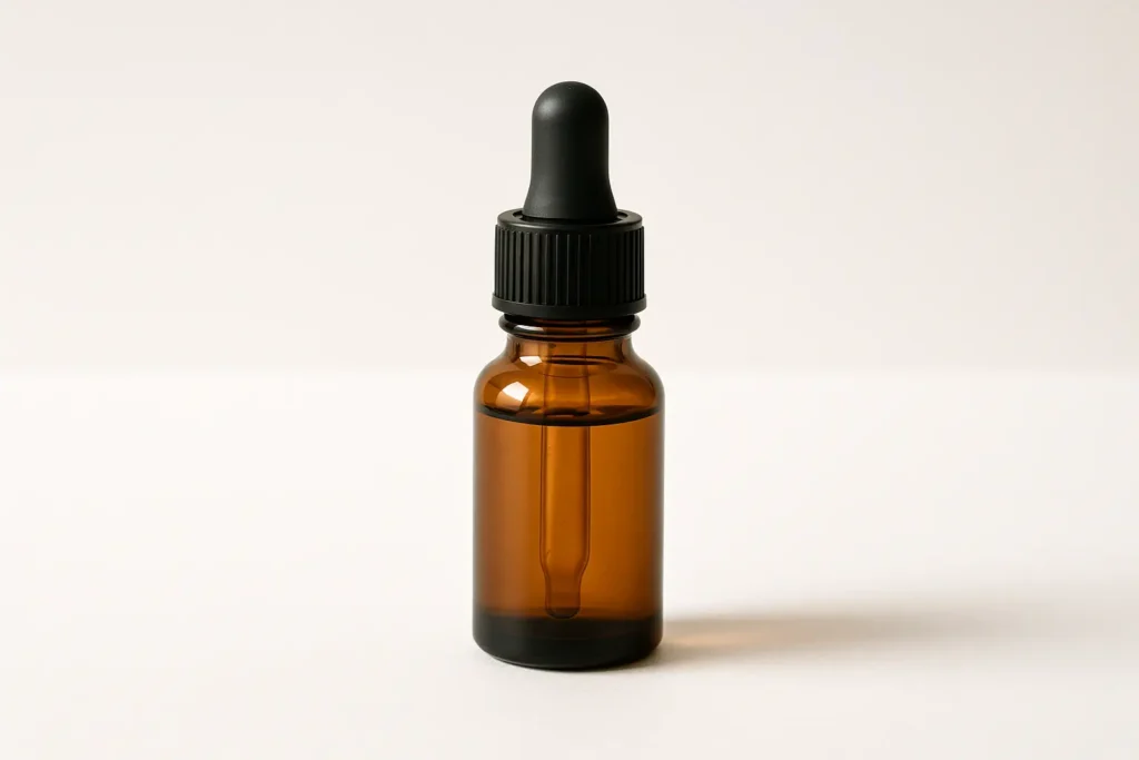 Amber glass dropper bottle representing a natural nail and skin wellness formula.
